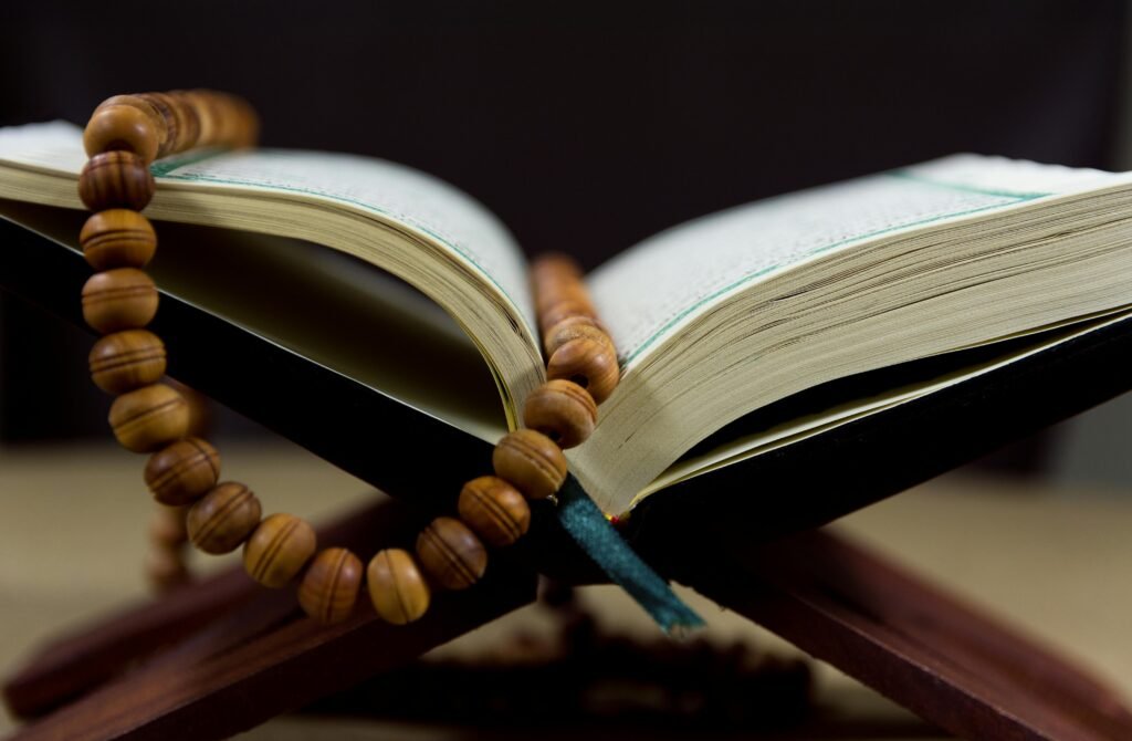 An open Quran with prayer beads on a wooden stand, symbolizing faith and spirituality.